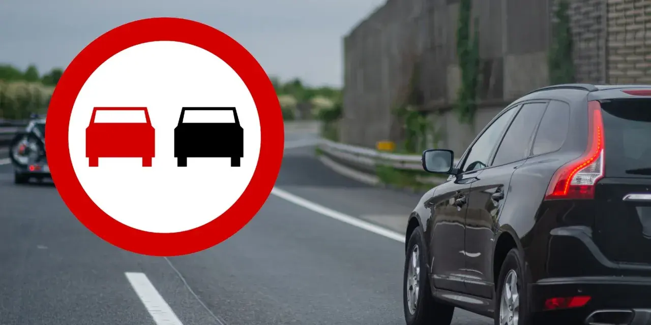 Znak zakazu wyprzedzania na drodze. Czarny SUV jedzie po prawej stronie, a z lewej widać znak z dwoma samochodami.