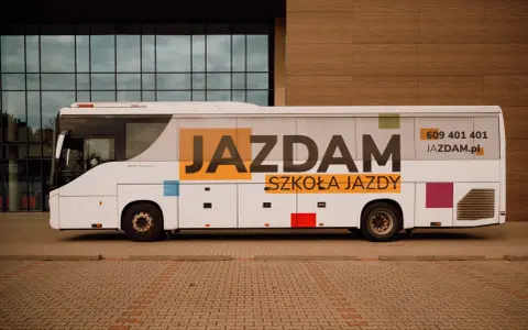 Biały autobus szkolny z napisem "JAZDAM SZKOŁA JAZDY" i numerem telefonu. Idealny do nauki jazdy kategorii D.
