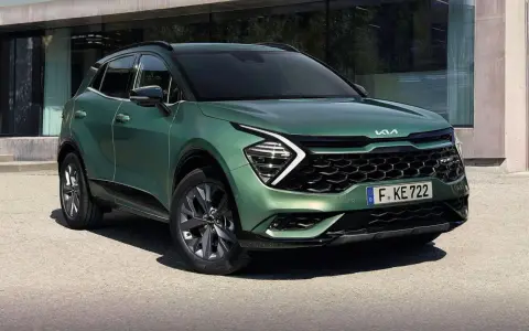 Nowy zielony Kia Sportage 1.6 benzyna z nowoczesnym designem, zaparkowany przed budynkiem.
