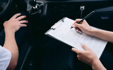 Kobieta wypełnia formularz rejestracji auta, siedząc obok kierowcy.