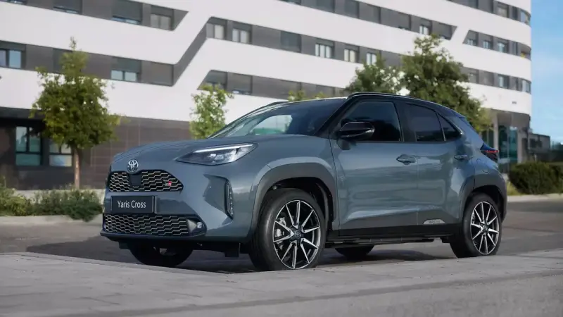 Szary Toyota Yaris Cross hybryda stoi na tle nowoczesnego budynku.