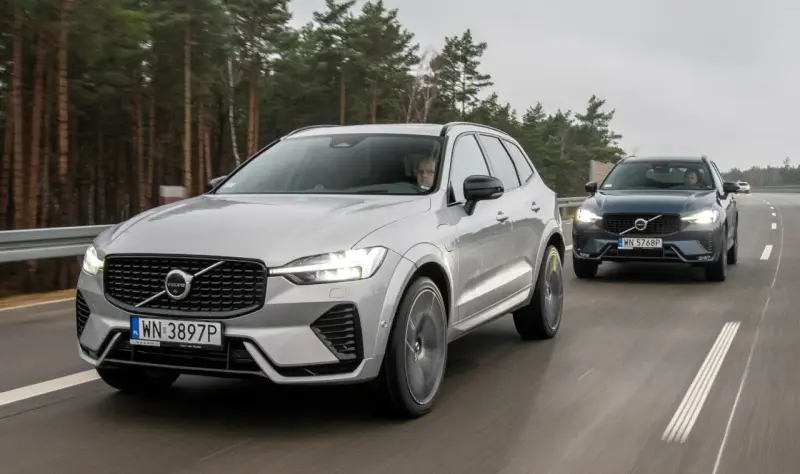 Dwa Volvo XC60 T8 jadące po drodze leśnej. Jeden srebrny, drugi ciemnoszary.
